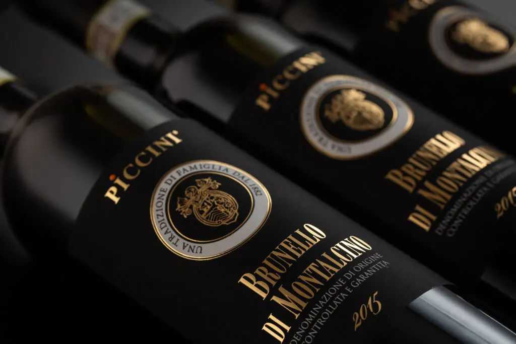 “colombia no es una apuesta, sino una historia que se extiende”, mario piccinni Botellas de vino de alta gama brunello di montalcino de piccini con etiquetas negras y letras doradas elegantes.