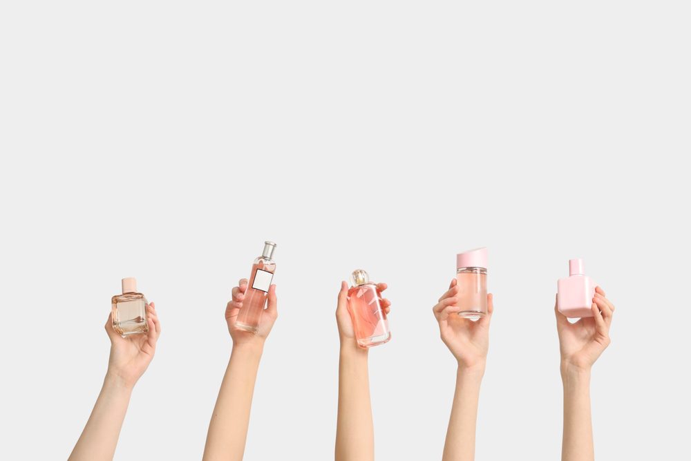 Manos con botellas de perfume haciendo layering de perfumes